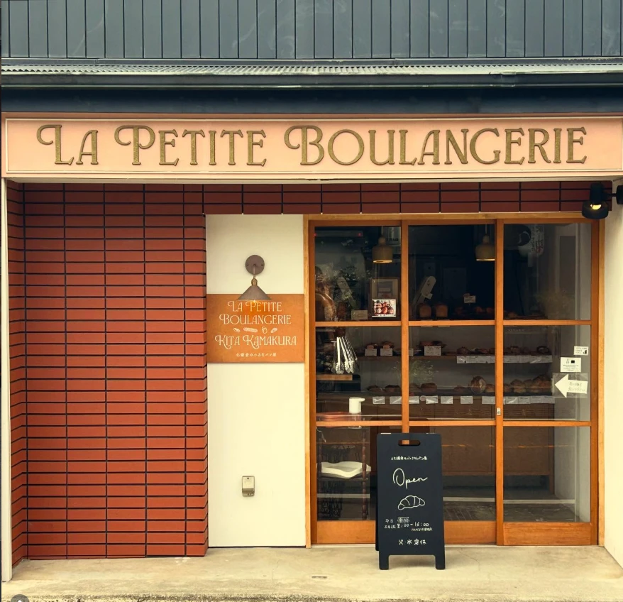 La Petite Boulangerie Kita Kamakura の外観。サーモンピンクの看板に金色の文字。